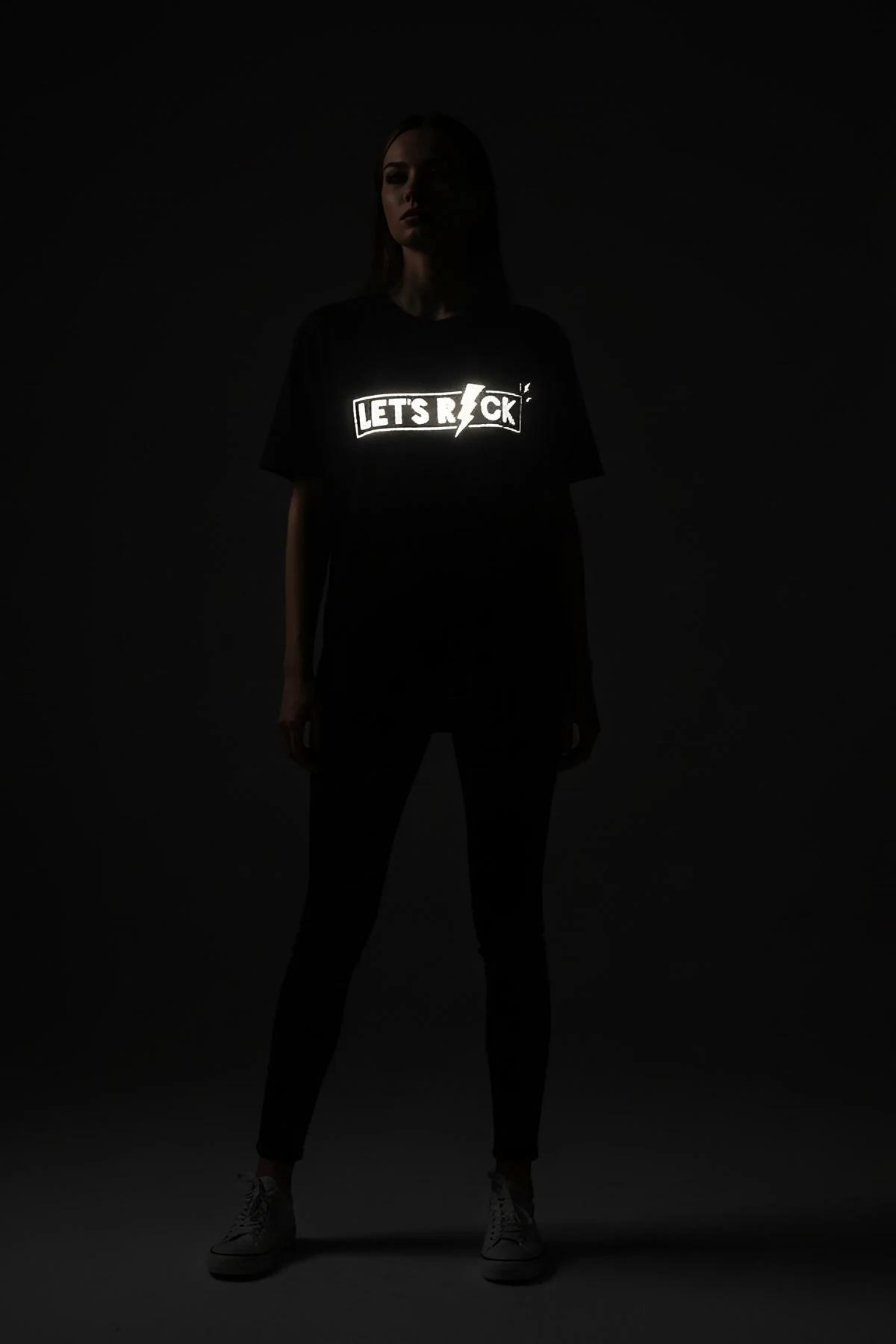 LET'S ROCK şimşek ikonlu reflektör baskılı siyah oversize tişört, ışık altında parlayan ön baskı, model üzerinde