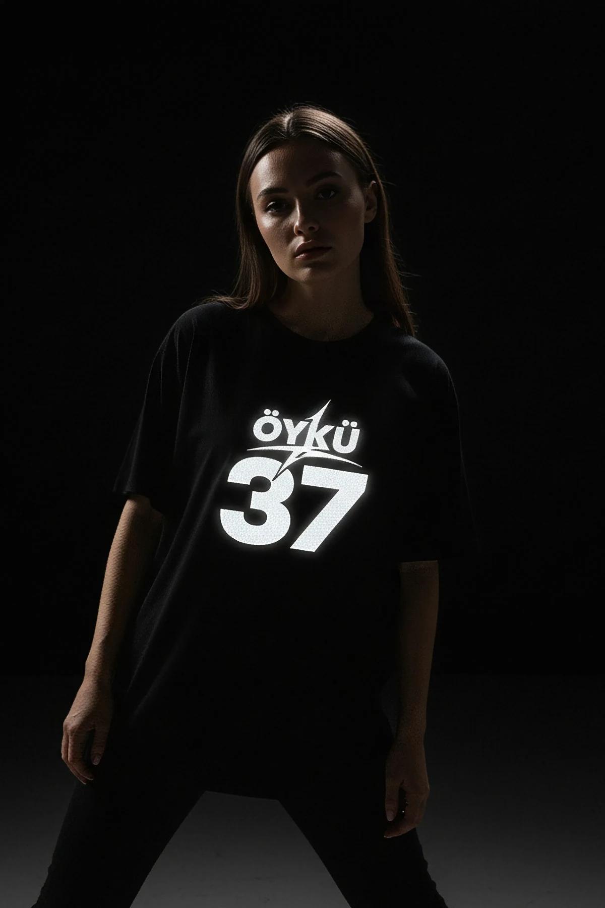 ÖYKÜ 37 reflektörlü ön baskılı siyah oversize tişört, yıldırım grafik detaylı, model üzerinde