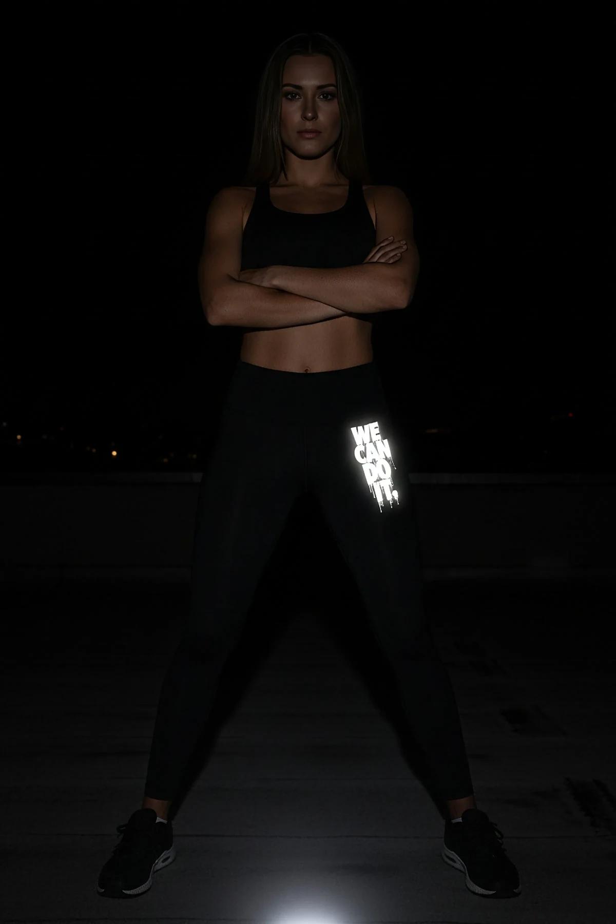 reflektörlü siyah spor tayt sol bacak yanında WE CAN DO IT motivasyon baskısı gece koşu görünümü
