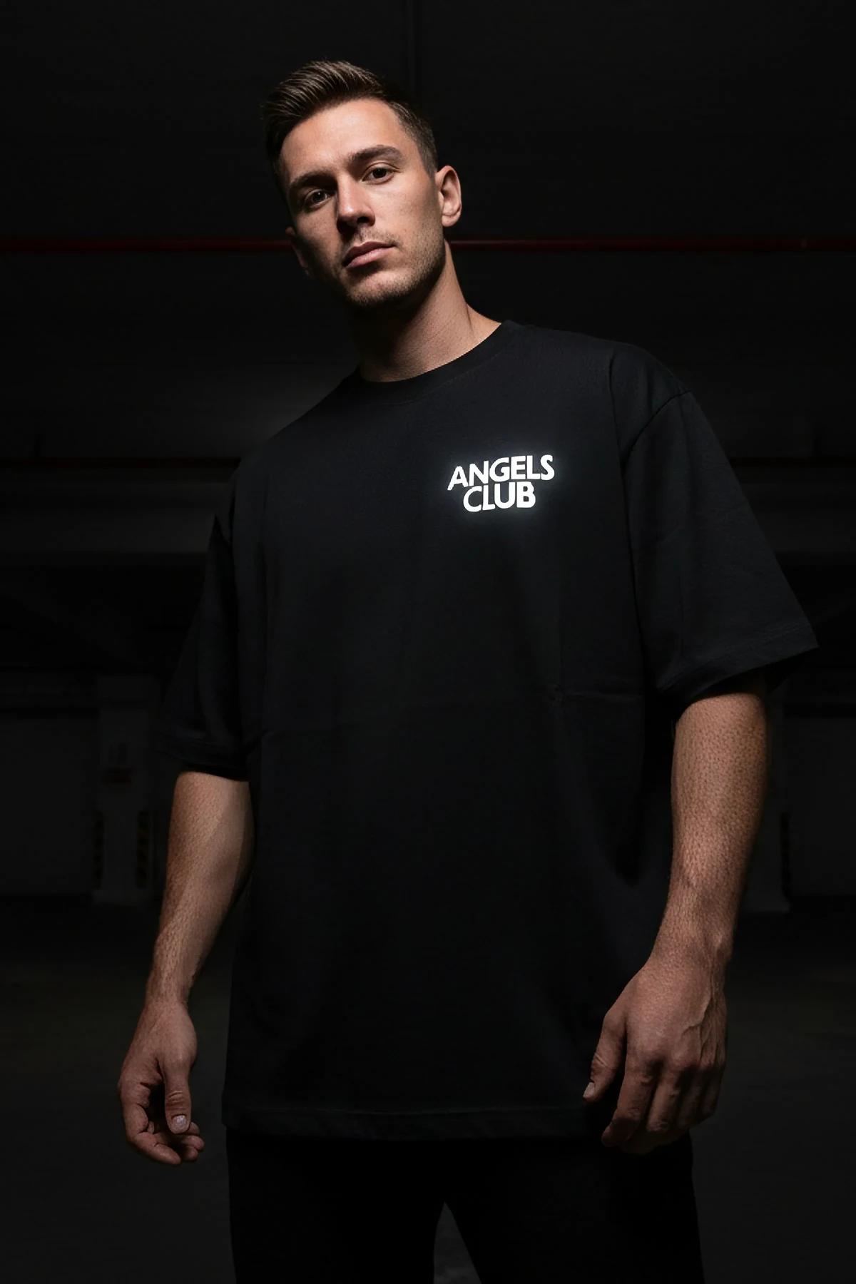 Black oversized t-shirt with reflective Angels Club left-chest print, boxy drop-shoulder silhouette, worn by male model
