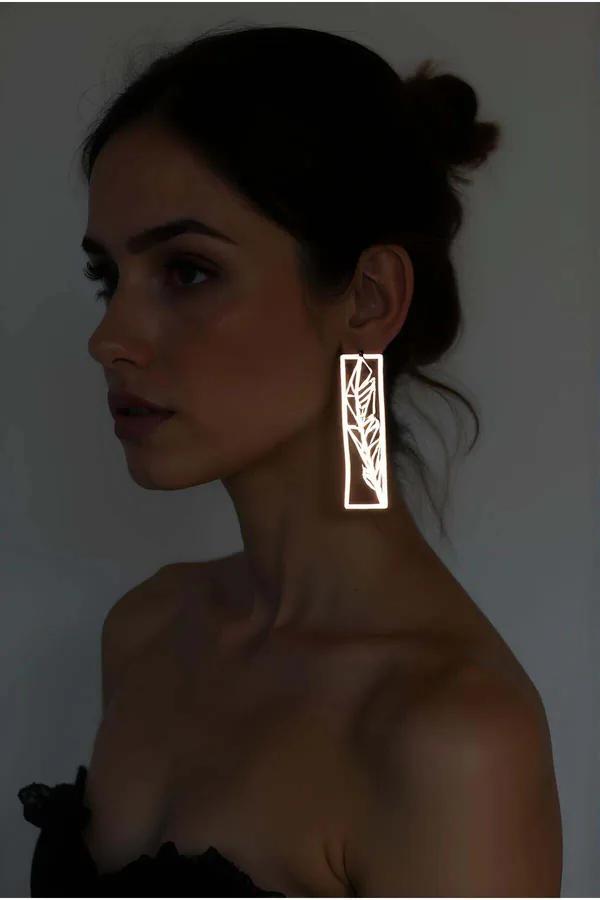 Silver laser-cut rectangle feather earrings with botanical leaf cutout worn as a long drop statement earring