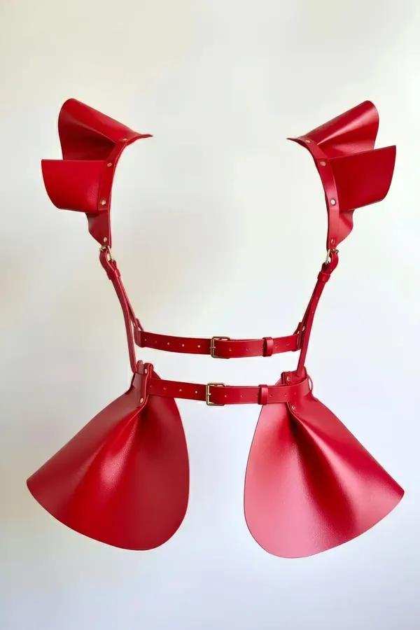 Red faux leather flounce harness skirt with fan-shaped shoulder panels and curved hip flounces, gold-tone buckle hardware, ba