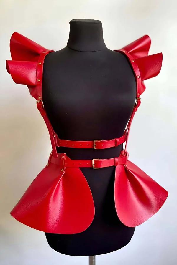 Red faux leather harness with layered ruffled shoulders and curved peplum panels, gold-tone buckles, on mannequin