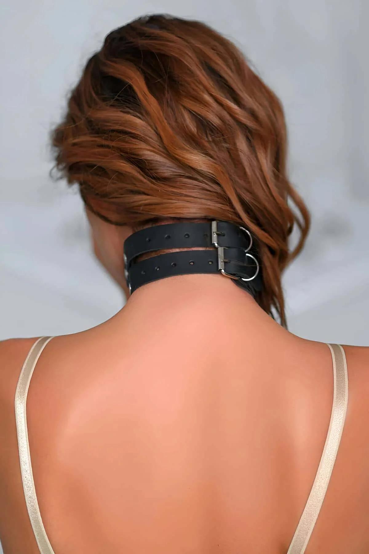 Wide black studded wrist cuffs with buckle closure and connector strap detail, front view