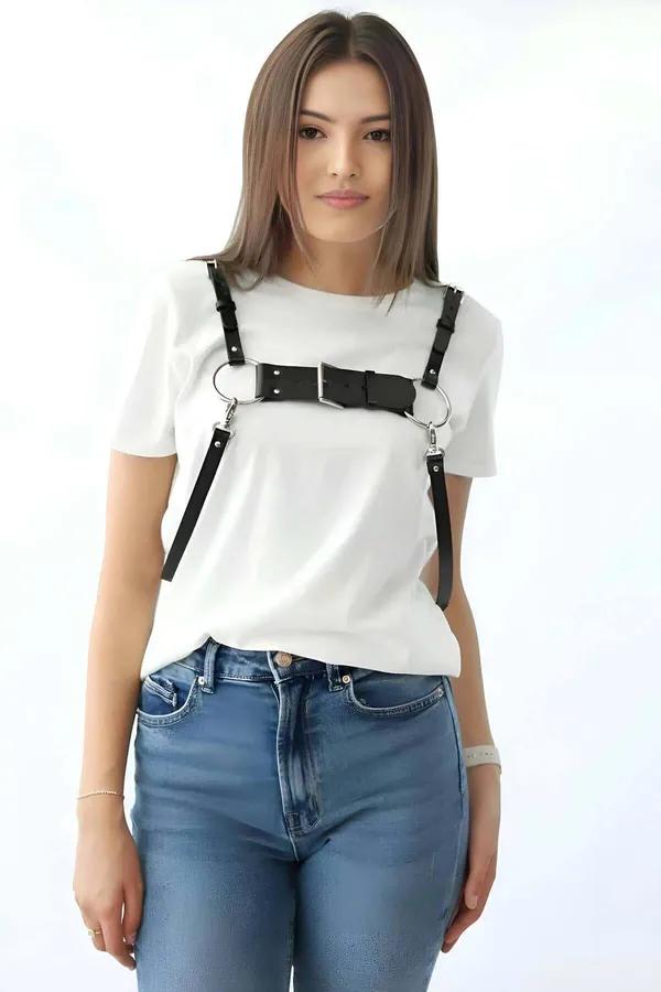 Black faux leather chest harness with wide buckle bar and twin silver O-rings worn over white t-shirt
