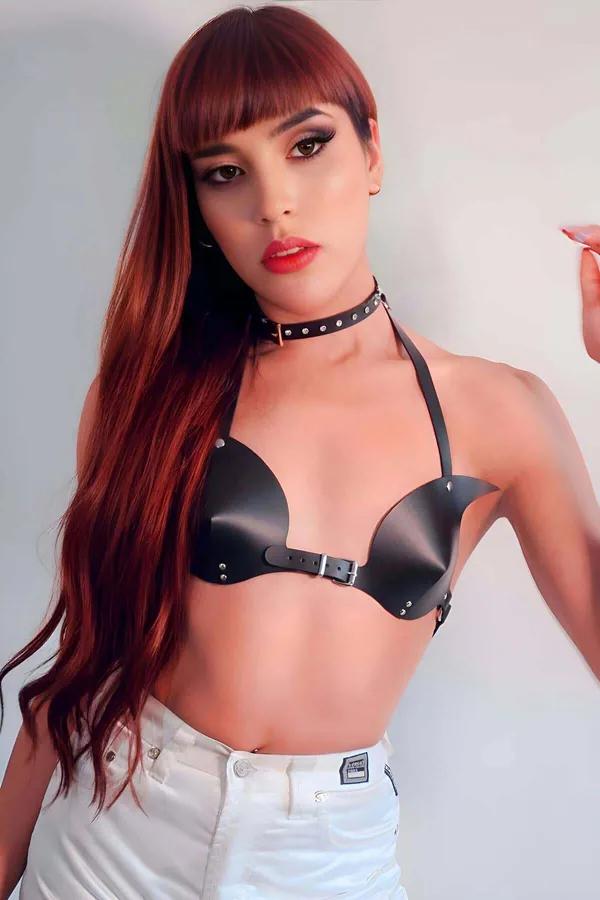 Black faux leather bra harness with molded cups silver stud trim and front buckle closure worn with white jeans