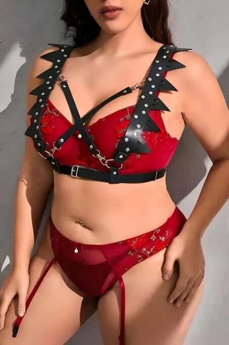 Black faux leather chest harness with triangular spike trim and silver studs worn over red lace lingerie
