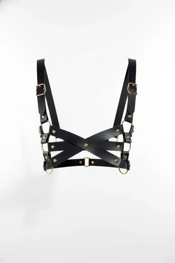 Black faux leather chest harness with X-cross strap pattern and gold-tone buckles and O-rings on white background