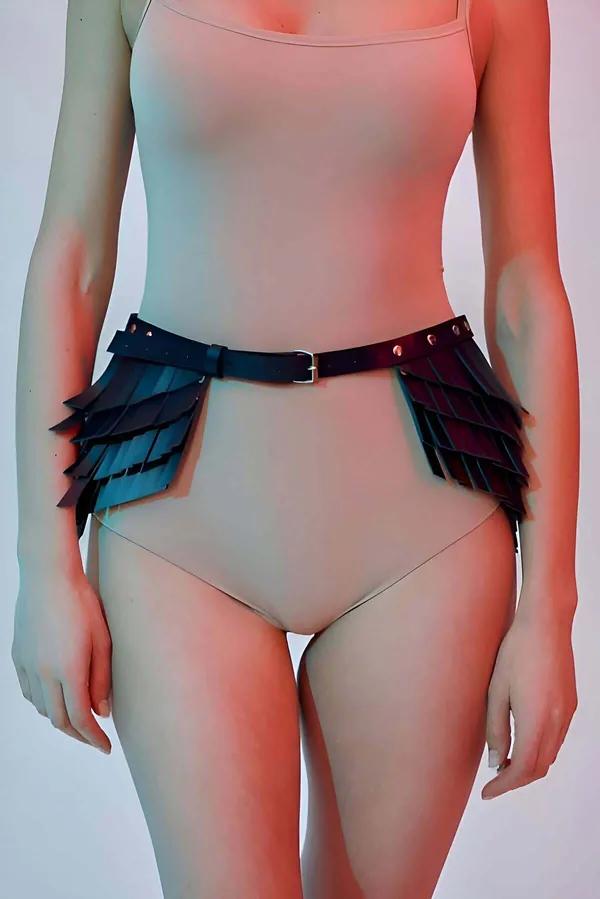 Black faux leather scaled waist harness skirt with overlapping panel layers and silver square buckle, worn over nude bodysuit