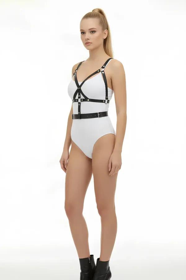 Black faux leather caged body harness with silver studded waist belt worn over white bodysuit, front three-quarter view