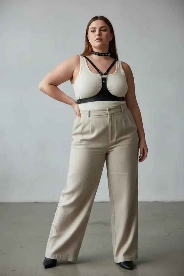 Black faux leather chest harness with studded choker and silver O-ring worn over cream tank top