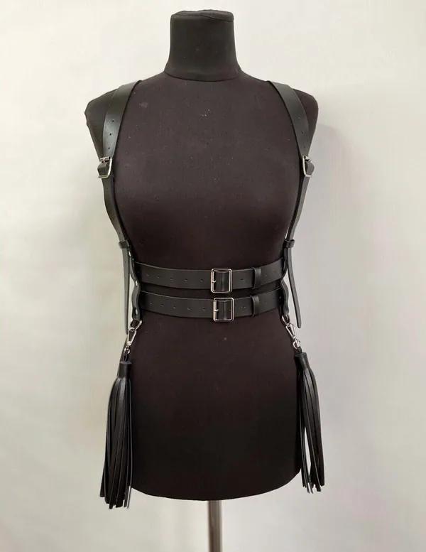 Black faux leather strappy body harness with double waist belts and long tassel fringe hanging from silver D-rings