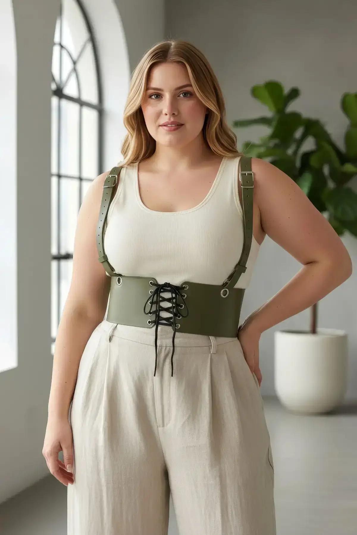 Olive green wide-band corset harness styled over white ribbed tank and linen trousers