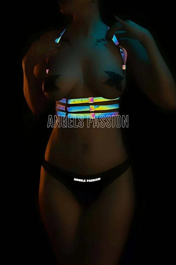 Iridescent full body harness with multi-band cage waistband and shoulder straps glowing pink teal and gold under UV festival 