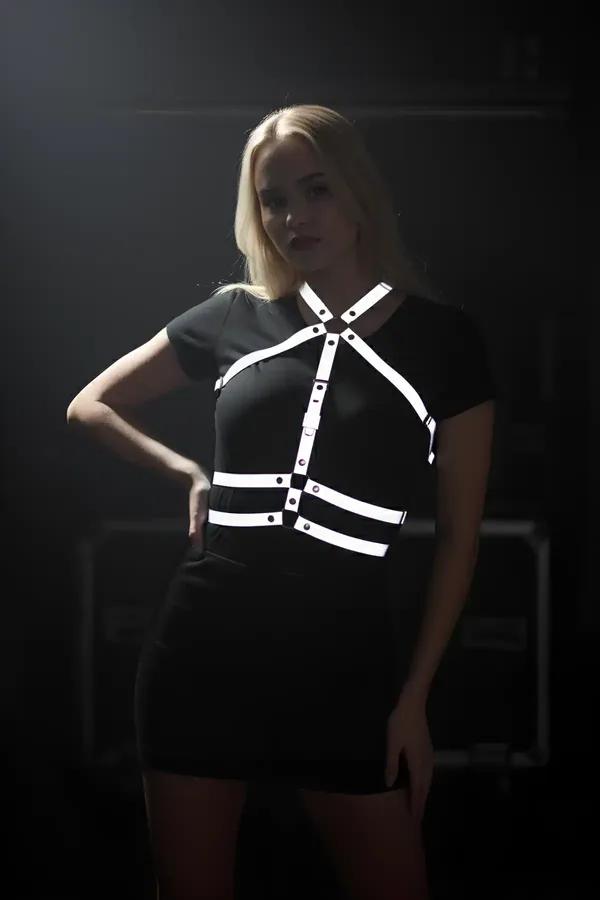 White reflective chest harness with X-cross strap design and chrome snap hardware worn over black outfit