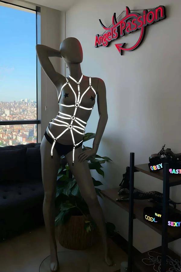 Black reflective body harness with white-glow cage straps and silver O-ring connectors displayed on mannequin