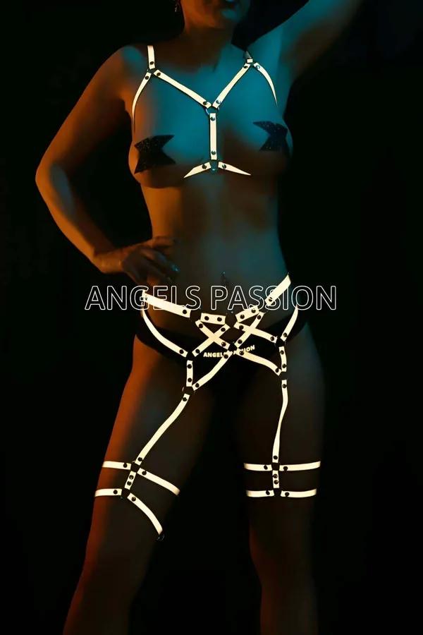 White reflective full body harness with chest cage straps, hip cross pattern, and double thigh garter bands under neon light