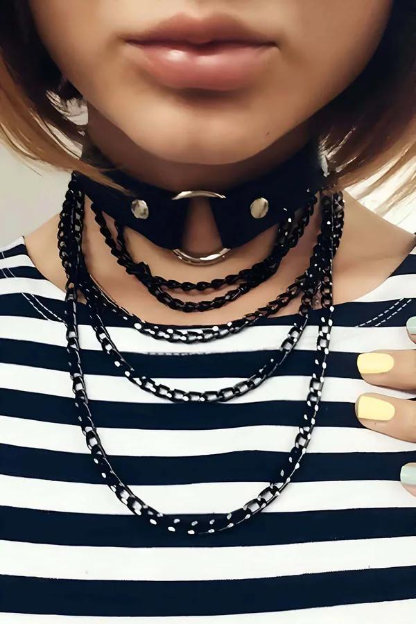 Black faux leather O-ring choker with three cascading black chain layers worn over a striped tee