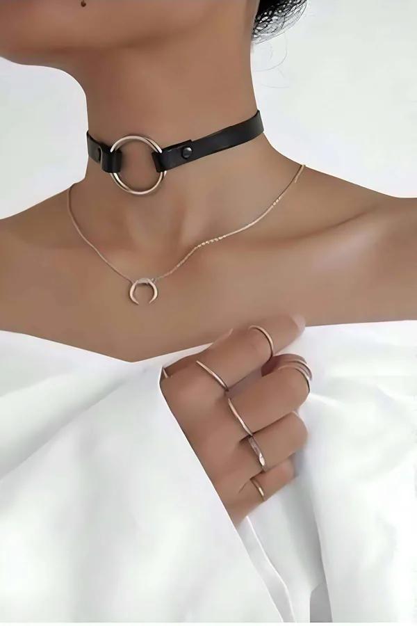 Black faux leather choker with large gold-tone O-ring detail worn at base of neck over white top