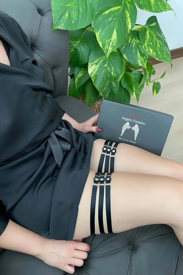 Black multi-strap garter leg harness with silver O-ring rivets worn on upper thigh over bare skin