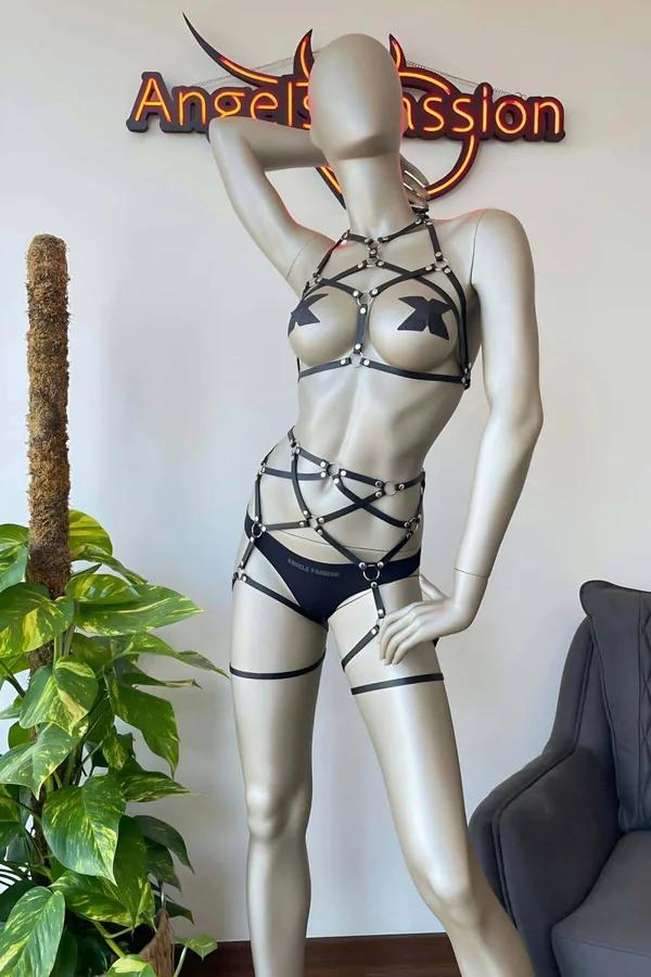Black faux leather multi-strap full body harness with silver O-rings, cross-strap waist cage, brief, and thigh garters on man