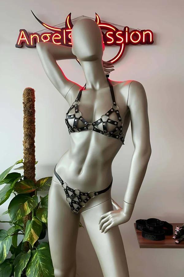 Black faux leather studded bra and thong harness set with silver O-rings and rivet details on mannequin