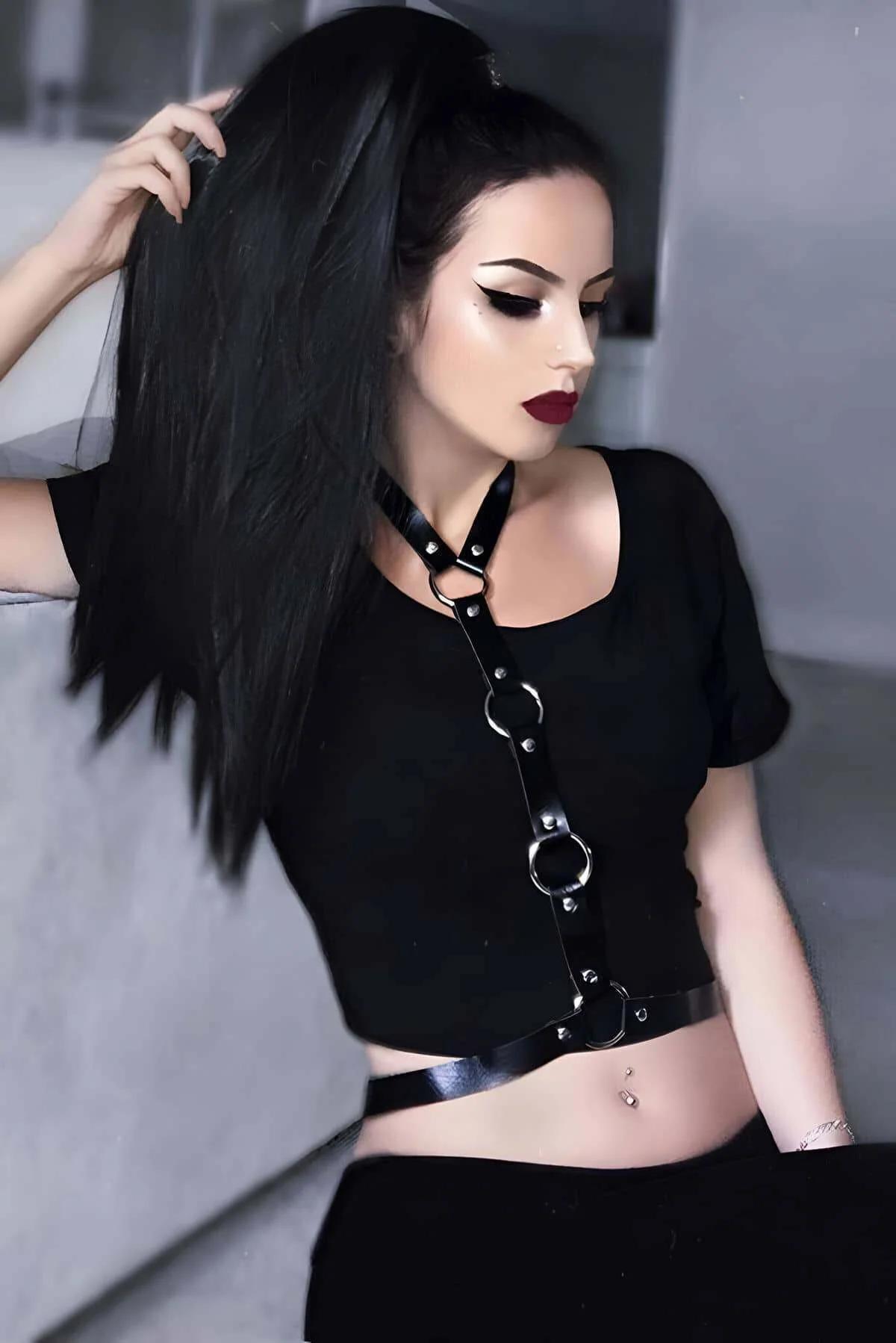 Black faux leather chest harness with three gunmetal O-rings and rivet studs, single collar-to-waist strap, worn over black t