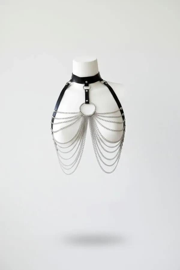Black faux leather chest harness with cascading silver-tone chains and centered O-ring on mannequin