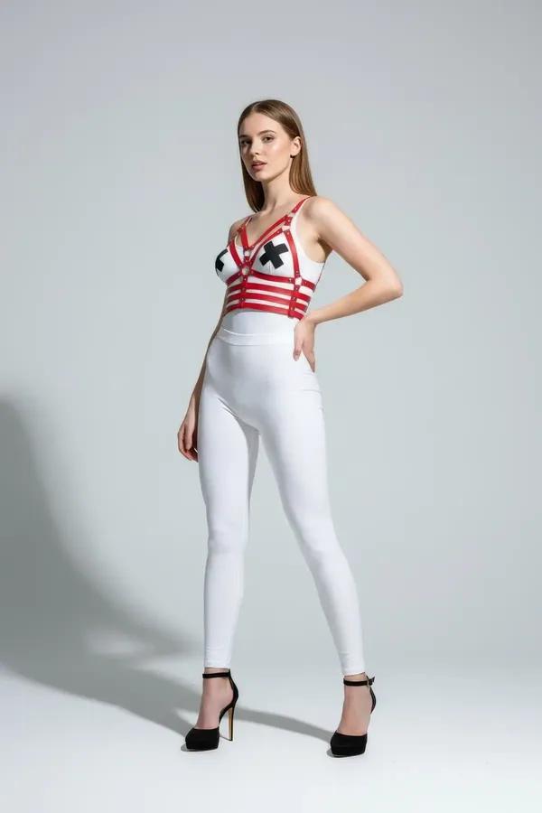 Red faux leather X-strap color block chest harness with gold-tone O-rings worn over a white bodysuit