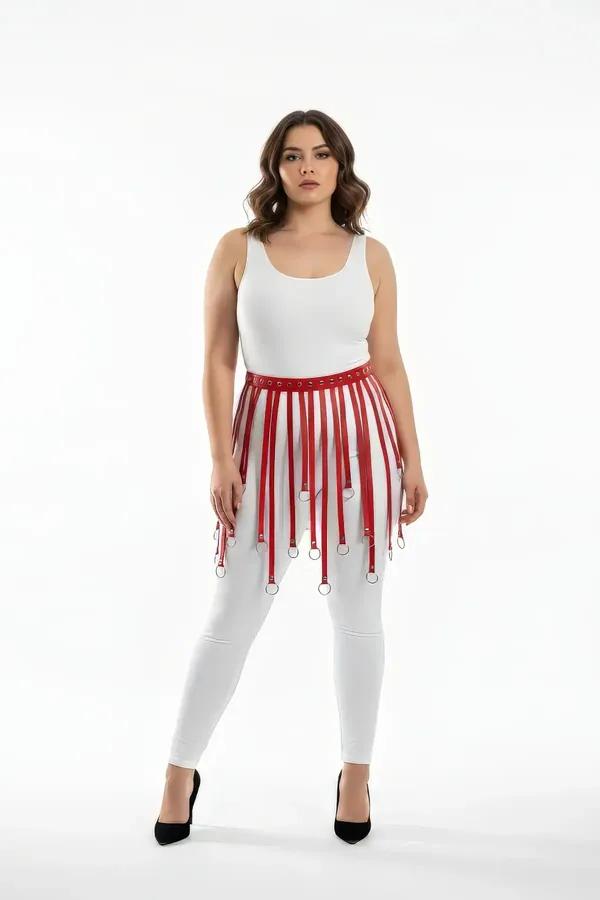 Red faux leather fringe skirt harness with multiple vertical straps each ending in a silver O-ring worn over white jeans