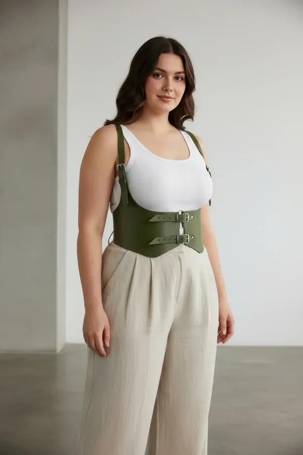 Olive faux leather waist harness with double silver buckles and shoulder straps worn over white tank top