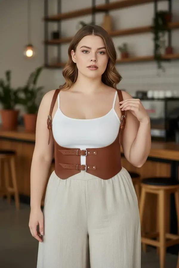 Tan faux leather underbust harness waist belt with dual gold buckles and adjustable shoulder straps worn over white tank