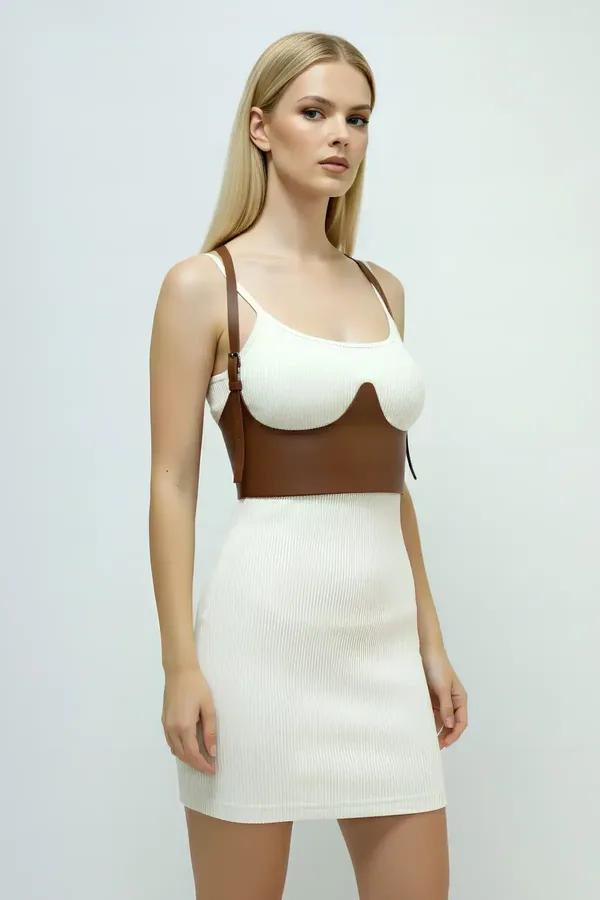 Brown faux leather underbust harness with sculpted molded cups and adjustable shoulder straps worn over white ribbed dress