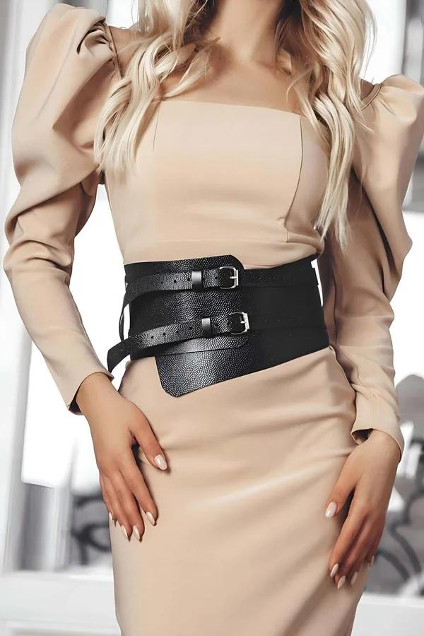 black wide faux leather corset belt with two silver pin buckles worn over beige midi dress showing pebbled texture