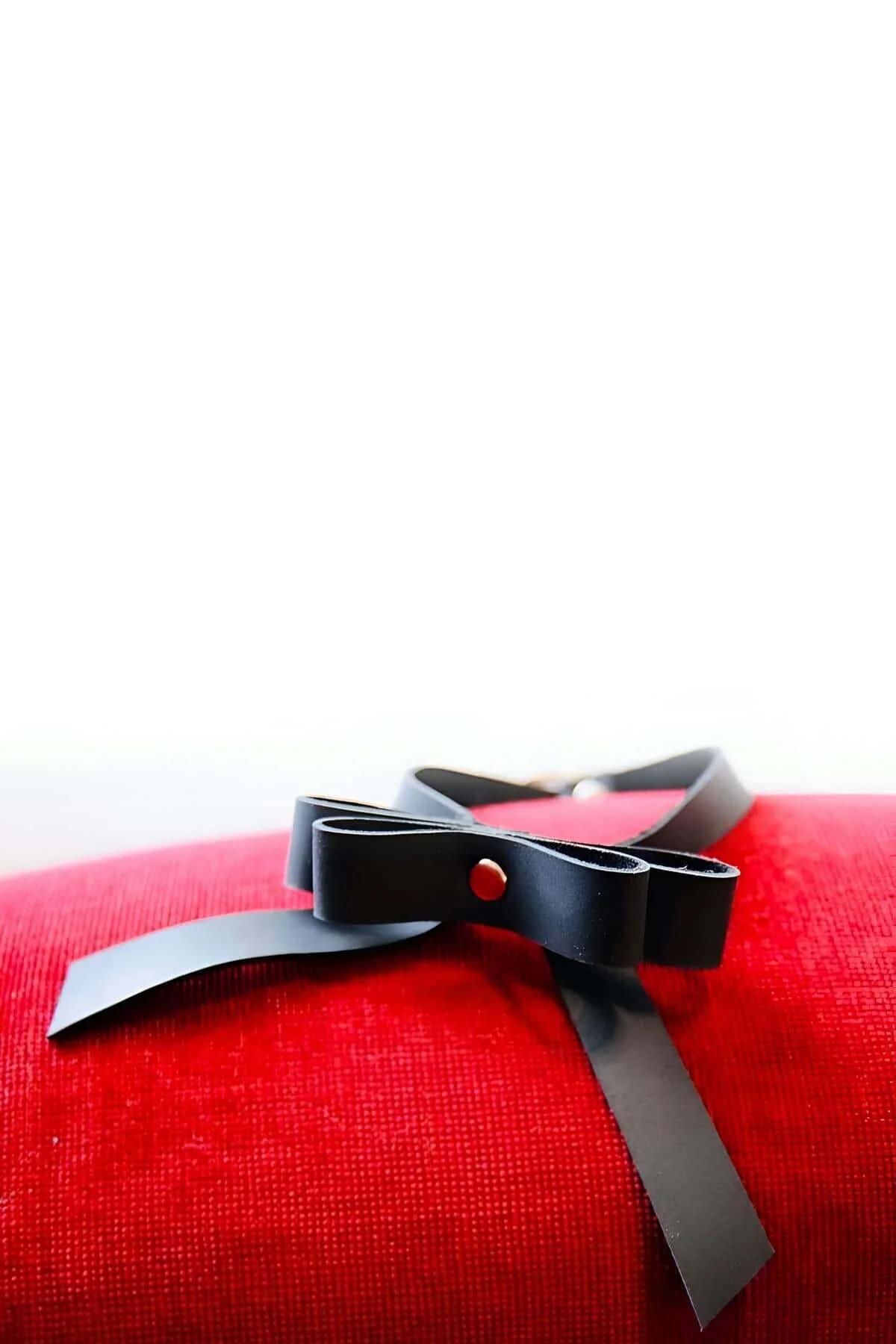 close-up of matte black faux leather bow knot with single silver-tone rivet detail