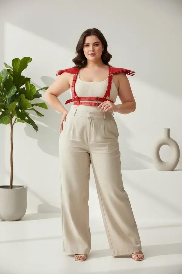 Red faux leather chest harness with fan-shaped shoulder spikes and silver rectangular buckles worn over cream top