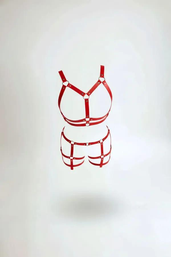 Red faux leather chest harness and cage garter belt set with silver O-rings and stud rivets on white background