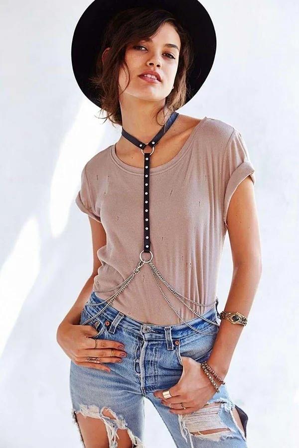 Black faux leather studded halter body harness with silver O-ring and draped waist chains worn over a t-shirt