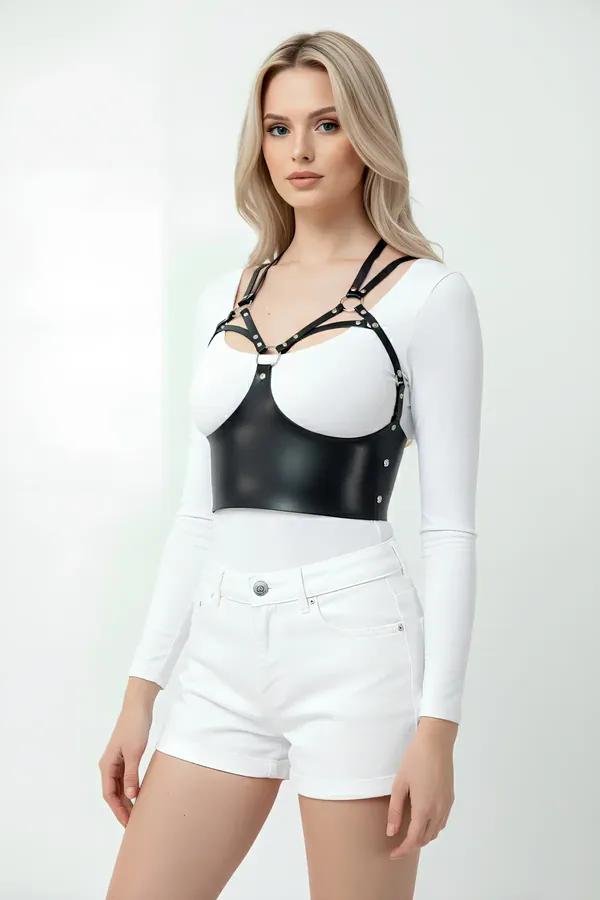 black faux leather bustier harness with silver studs and dual shoulder straps worn over white long-sleeve top