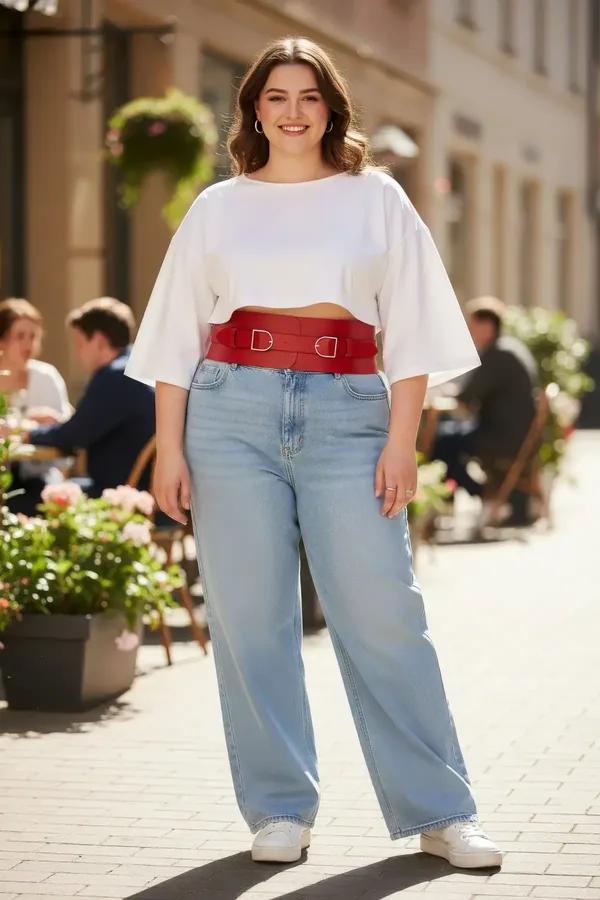 Wide red faux leather waist harness with two silver D-ring buckles worn over white crop top and light-wash jeans