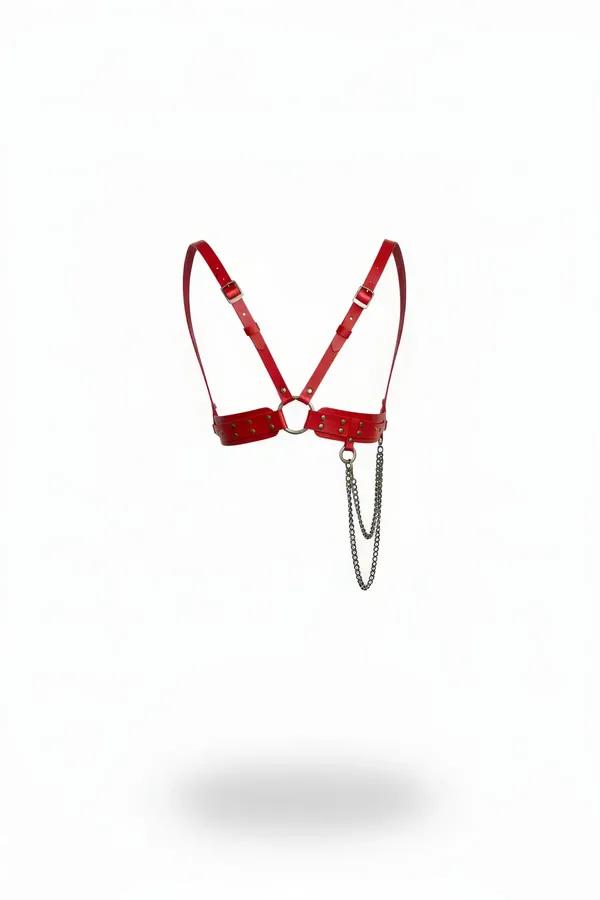 Red faux leather chest harness with gold studs, central O-ring and draped silver-tone chain on white background