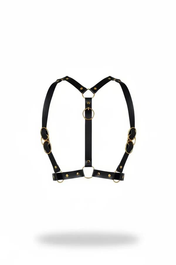 Black faux leather chest harness with six gold O-rings and rivet studs in a Y-strap silhouette