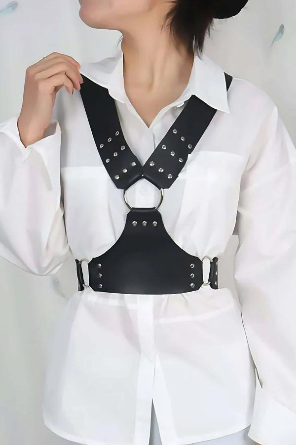 Black faux leather studded chest harness with silver O-ring center detail worn over white shirt