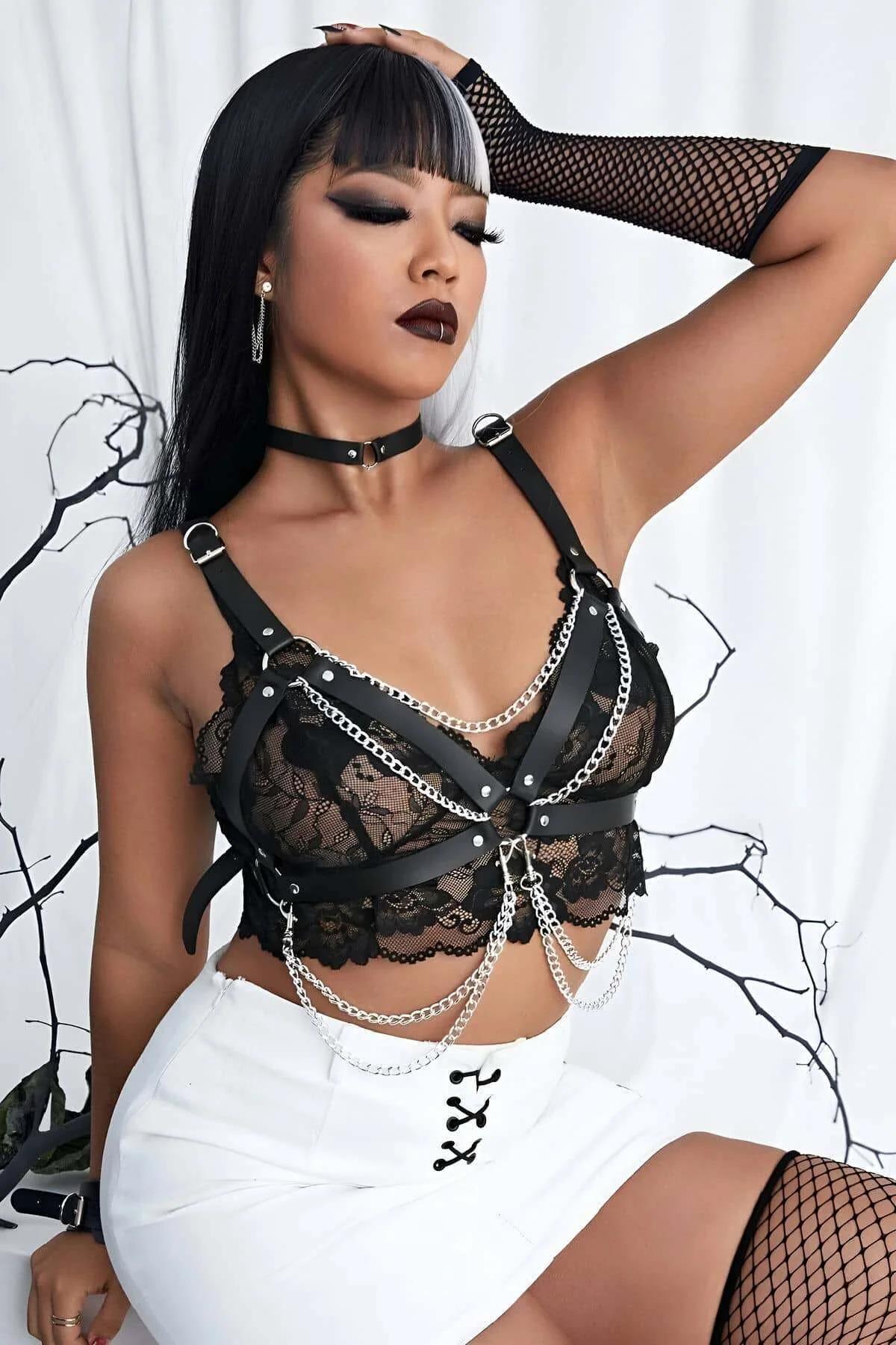 black faux leather chest harness with layered silver chains and O-ring hardware worn over black lace bralette