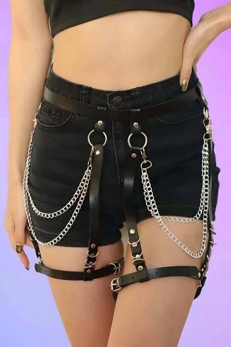 black faux leather garter harness with silver O-rings and double draping chain detail worn over denim shorts