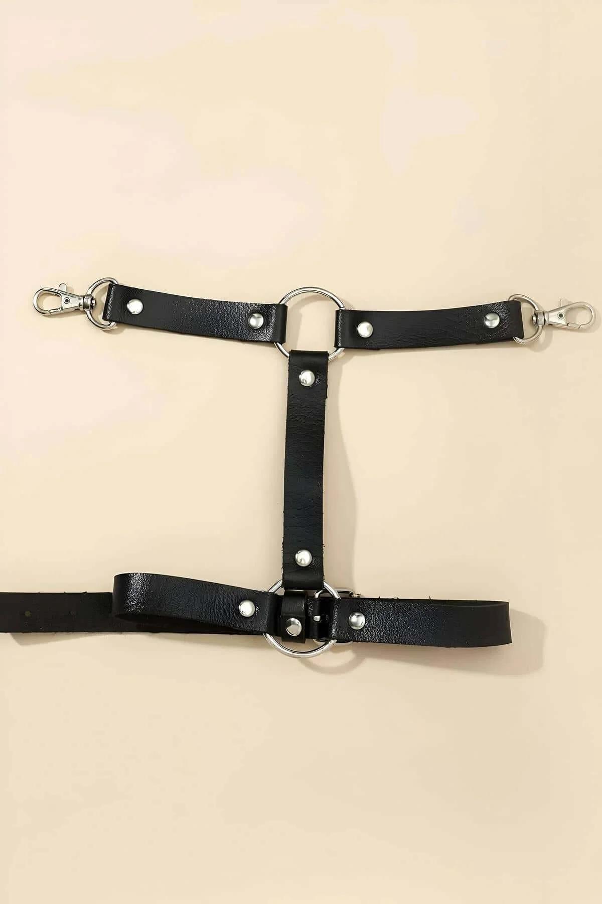 Close-up of silver swivel clip hardware fastening black faux leather garter strap to belt loop