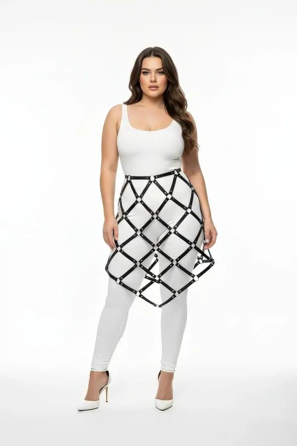 Black faux leather geometric cage skirt harness with silver rivet intersections worn over white leggings