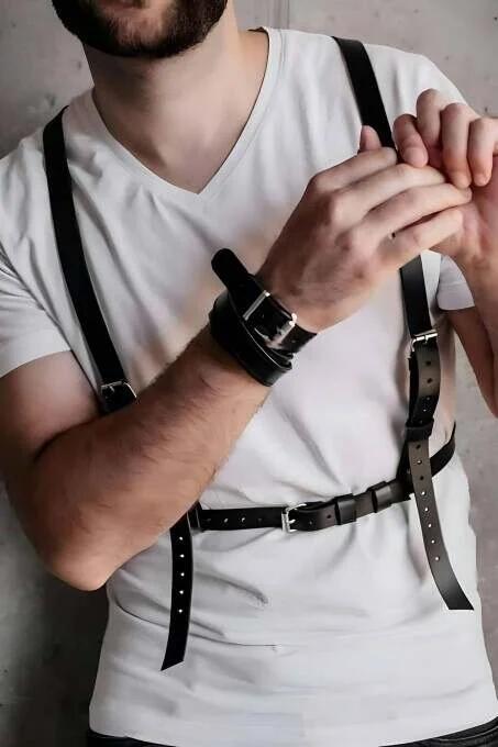 close-up of silver-tone pin buckle and punched adjustment holes on black faux leather chest harness strap