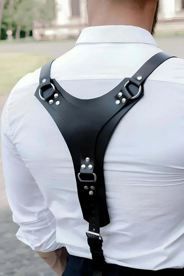 black faux leather Y-back body harness with silver O-rings and rivet studs worn over white shirt, rear view