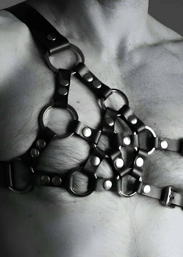 black faux leather chest harness with five silver O-rings caged front panel and adjustable shoulder straps on male torso